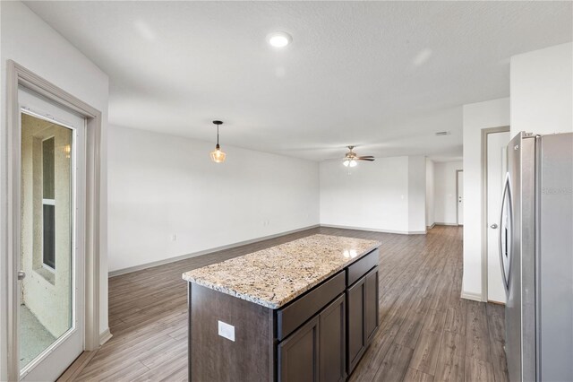 kitchen featuring dark brown cabinetry, light hardwood / wood-style floors, decorative light fixtures, and stainless steel fridge