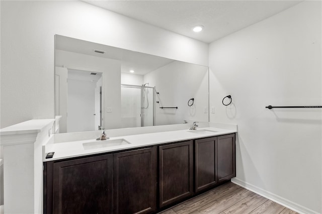 bathroom with wood-type flooring, vanity, and a shower with door