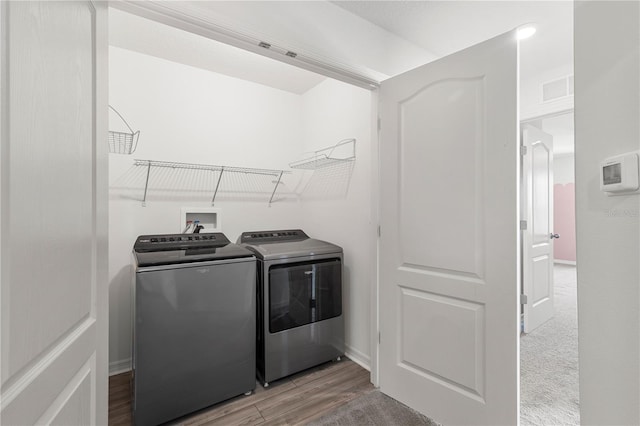 clothes washing area featuring light hardwood / wood-style floors and independent washer and dryer