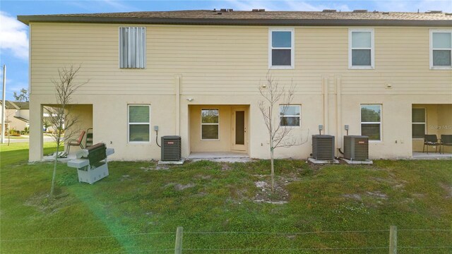 rear view of property with central AC unit and a yard