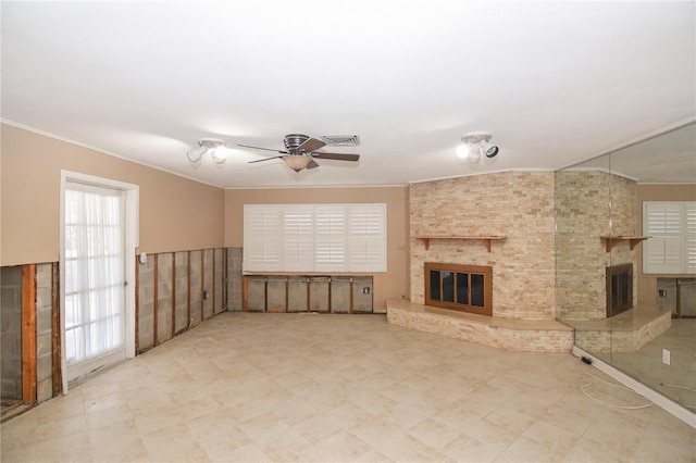 unfurnished living room featuring a fireplace, ceiling fan, and crown molding