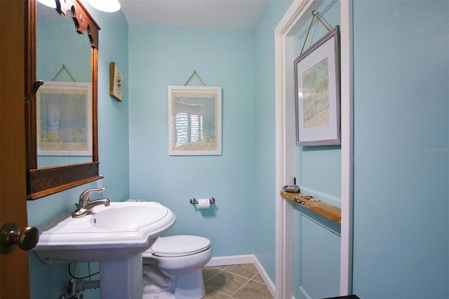 bathroom with toilet, tile patterned flooring, and sink