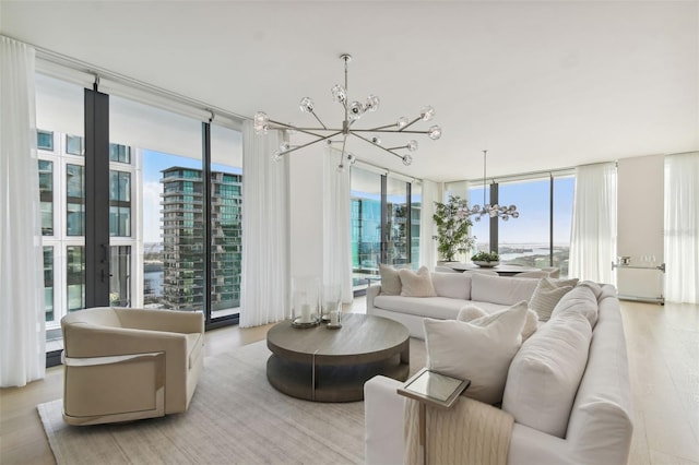 living room featuring a wall of windows, a notable chandelier, and light hardwood / wood-style floors