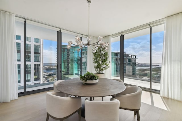 dining space featuring expansive windows, light hardwood / wood-style floors, and an inviting chandelier