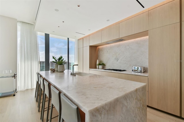 1000 Water St Unit 1702, Tampa, FL 33602 - kitchen featuring a sink, modern cabinets, light brown cabinetry, gas cooktop, and tasteful backsplash