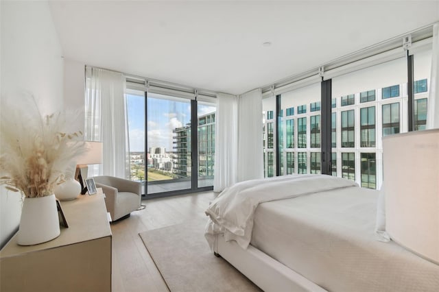 bedroom featuring expansive windows, access to exterior, and light hardwood / wood-style flooring