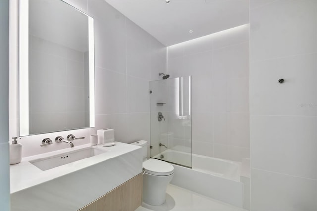 full bathroom featuring tile patterned flooring, vanity, toilet, tile walls, and tiled shower / bath combo