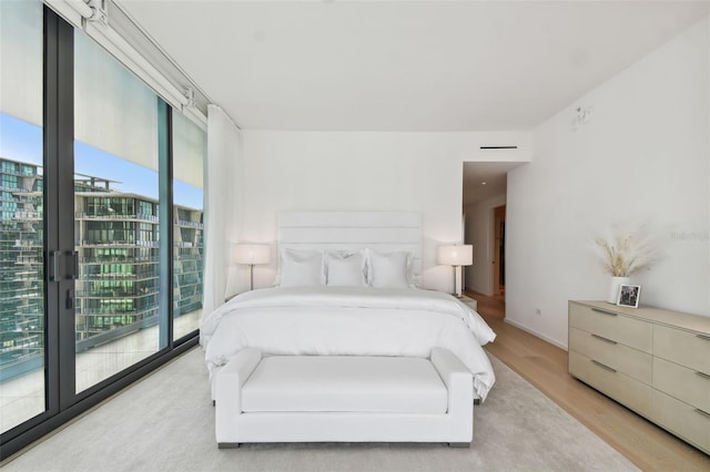 bedroom featuring access to outside, light hardwood / wood-style flooring, and multiple windows