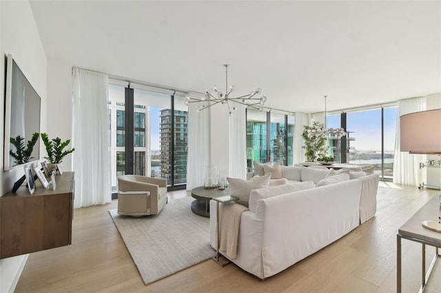 living room featuring a chandelier, light wood-type flooring, and floor to ceiling windows