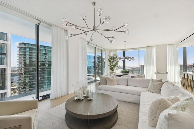 living room with expansive windows, light wood-type flooring, plenty of natural light, and a chandelier