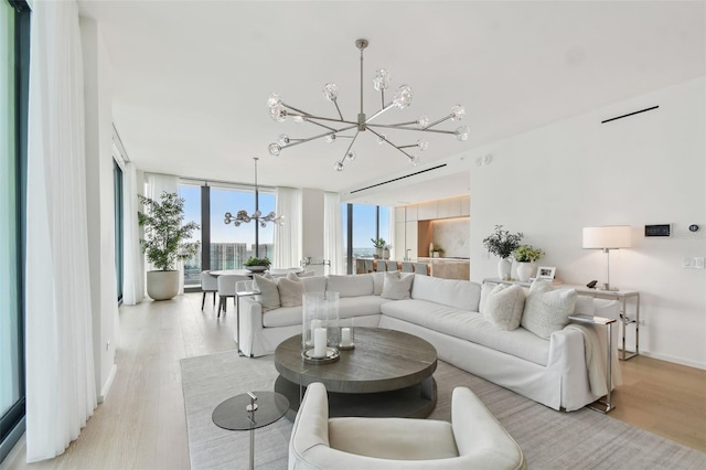 living room with expansive windows, a notable chandelier, and light hardwood / wood-style flooring