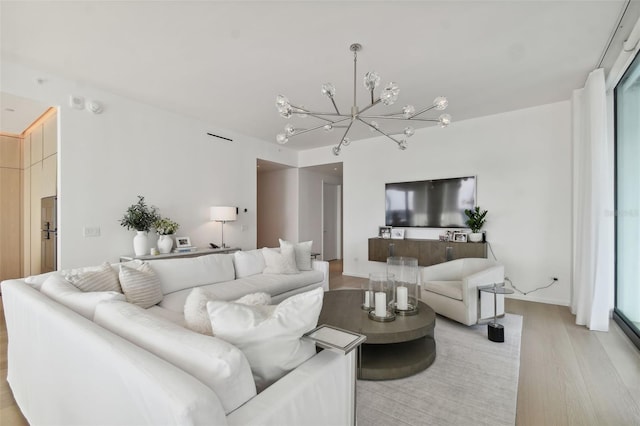 living room with an inviting chandelier and light wood-type flooring