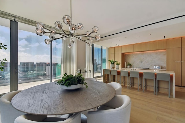 dining room with expansive windows, light wood-type flooring, and a notable chandelier