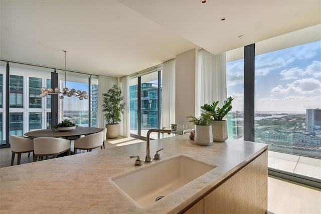 1000 Water St Unit 1702, Tampa, FL 33602 - kitchen featuring a sink, expansive windows, a chandelier, hanging light fixtures, and light stone counters