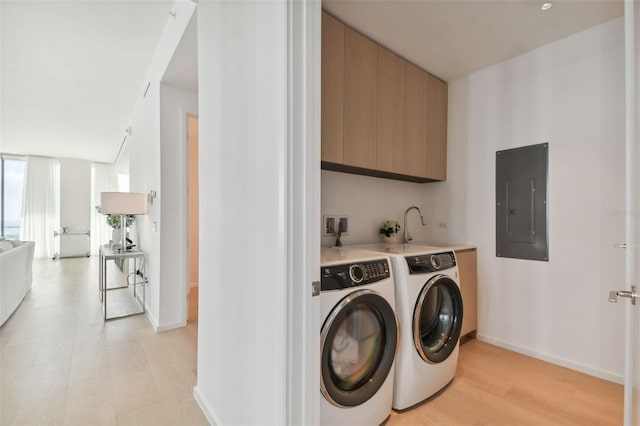 laundry area featuring electric panel, cabinets, washing machine and dryer, and light hardwood / wood-style flooring