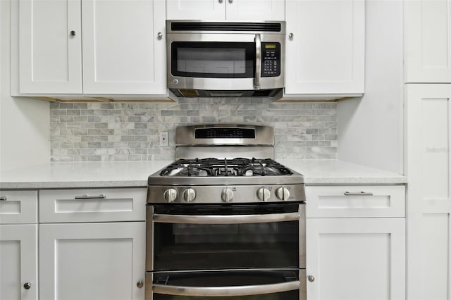 kitchen featuring stainless steel appliances, white cabinetry, and backsplash