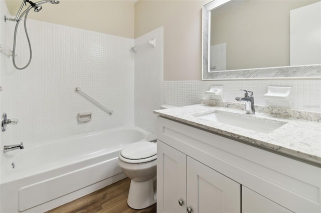 full bathroom with tile walls, tiled shower / bath combo, vanity, wood-type flooring, and toilet