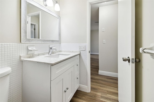 bathroom with tile walls, vanity, hardwood / wood-style flooring, and toilet