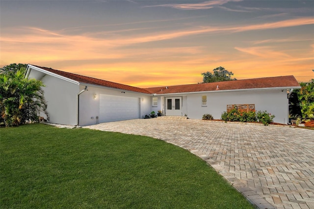 ranch-style house featuring a garage, french doors, and a yard