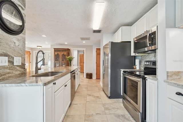 kitchen with tasteful backsplash, sink, stainless steel appliances, white cabinets, and light stone counters