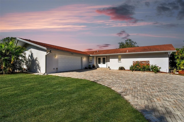 single story home featuring french doors, a yard, and a garage