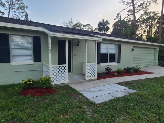 single story home featuring a garage, a yard, and covered porch