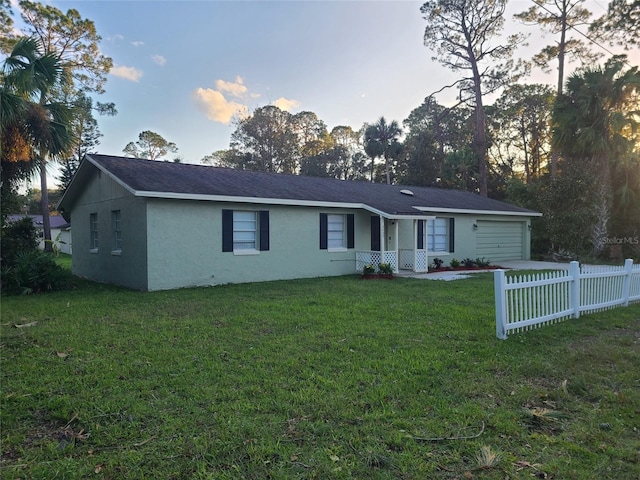 single story home featuring a garage and a yard