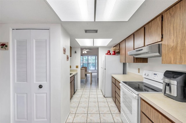 kitchen featuring ceiling fan, light tile patterned flooring, a skylight, and white appliances