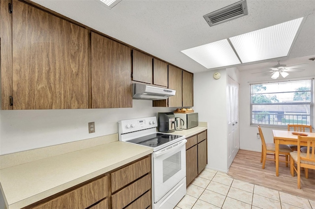 kitchen with ceiling fan, white electric stove, a textured ceiling, and light tile patterned floors