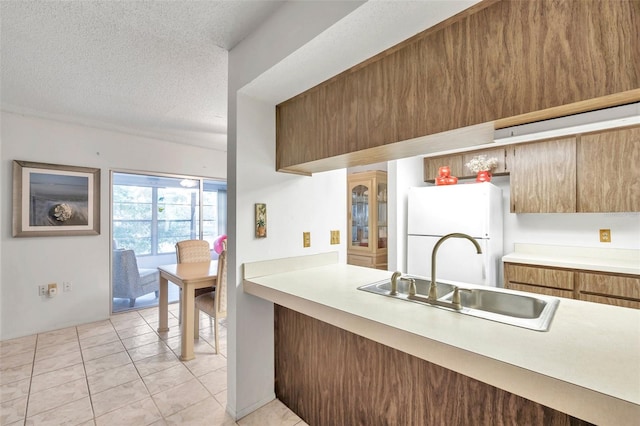 kitchen featuring light tile patterned floors, sink, white fridge, and a textured ceiling