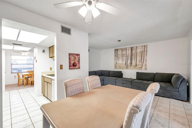 dining space with ceiling fan, a textured ceiling, and light tile patterned floors