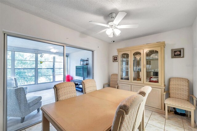 tiled dining room with a textured ceiling and ceiling fan