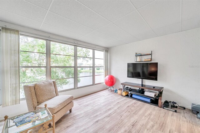 living area featuring plenty of natural light, wood-type flooring, and a drop ceiling