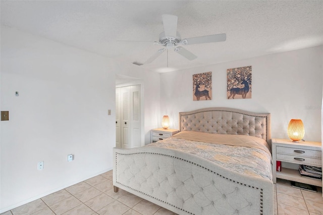 bedroom with ceiling fan, a textured ceiling, light tile patterned floors, and a closet