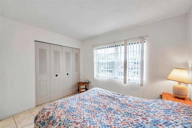 tiled bedroom with a closet and a textured ceiling