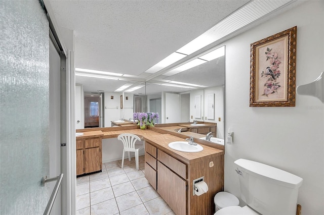 bathroom with a textured ceiling, toilet, vanity, and tile patterned flooring