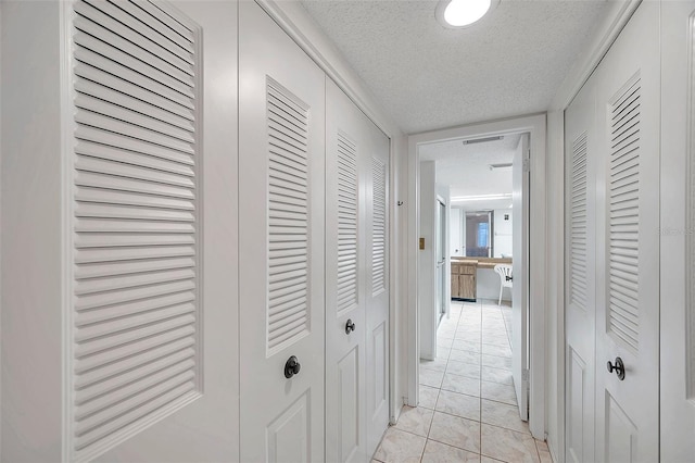 corridor with a textured ceiling and light tile patterned floors