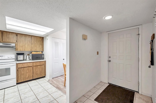 kitchen featuring a textured ceiling, light tile patterned floors, and white stove