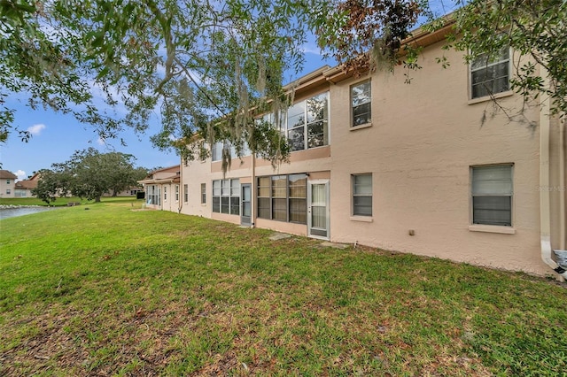 3840 Staysail Ln Unit 3840, Holiday, FL 34691 - rear view of property featuring stucco siding, a lawn, and a water view