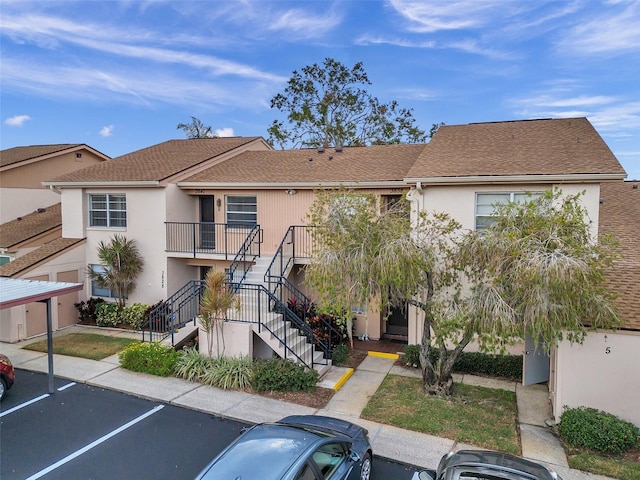 3840 Staysail Ln Unit 3840, Holiday, FL 34691 - view of front of house featuring uncovered parking, stucco siding, stairs, and roof with shingles