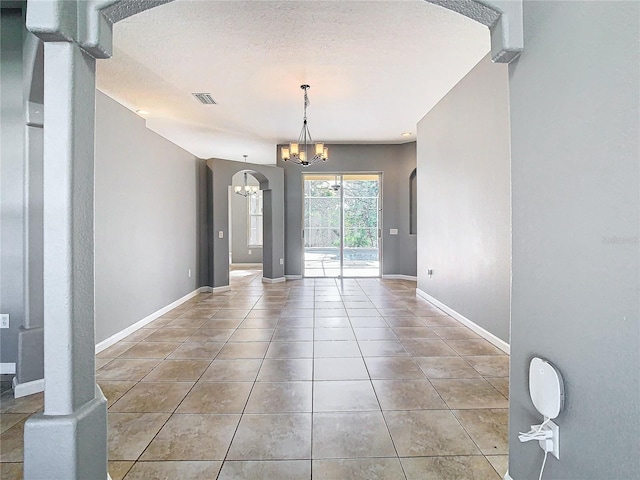 interior space with a textured ceiling, a chandelier, and tile patterned flooring