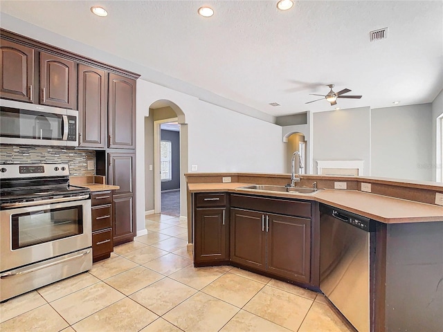 kitchen with dark brown cabinets, stainless steel appliances, sink, and light tile patterned floors