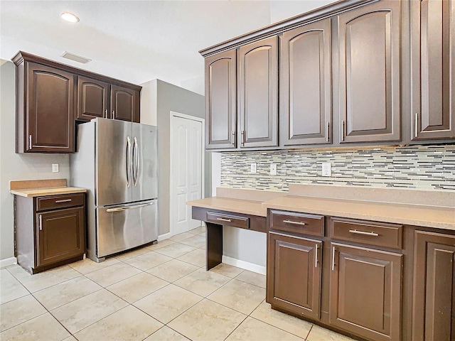 kitchen with stainless steel refrigerator, dark brown cabinets, and decorative backsplash