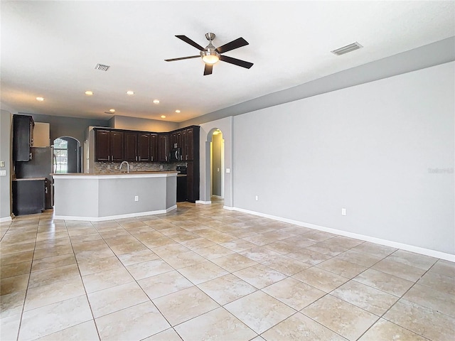 unfurnished living room featuring light tile patterned flooring, ceiling fan, and sink