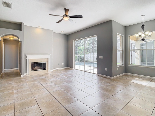 unfurnished living room with a fireplace, light tile patterned flooring, and ceiling fan with notable chandelier