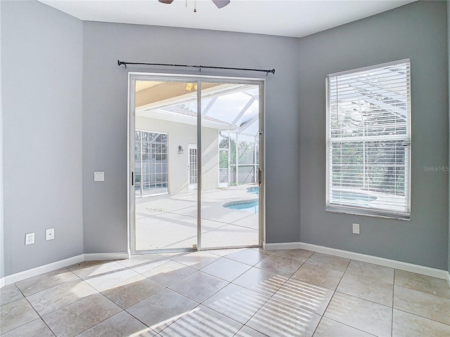 empty room featuring a healthy amount of sunlight, light tile patterned floors, and ceiling fan