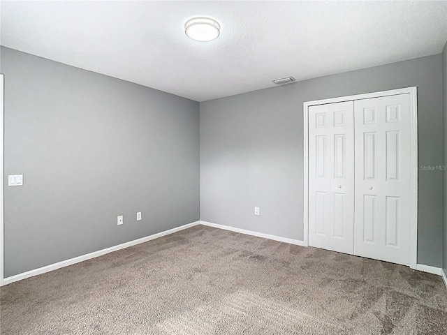 unfurnished bedroom featuring carpet floors, a closet, and a textured ceiling