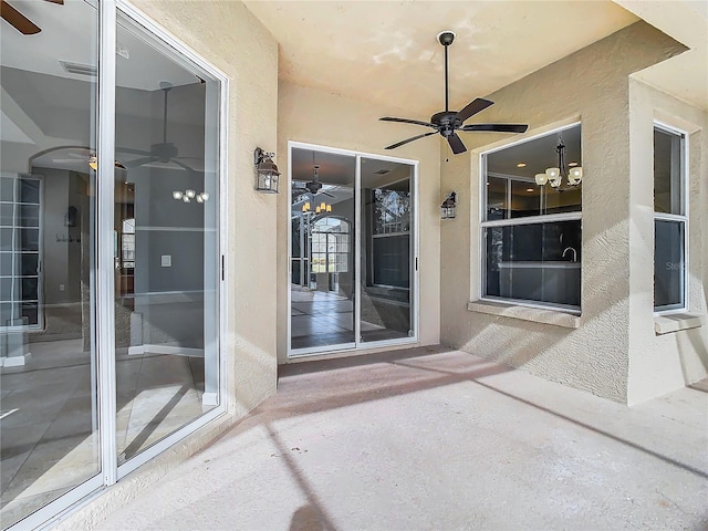 view of exterior entry with ceiling fan and a patio area