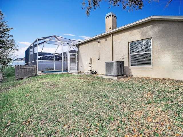 back of property featuring cooling unit, a yard, a swimming pool, and glass enclosure