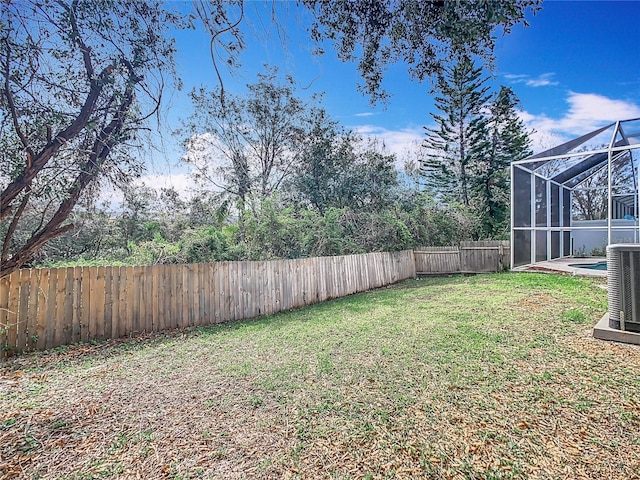 view of yard with central air condition unit and a lanai